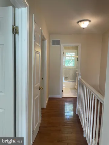 a view of a hallway with wooden floor and a bathroom