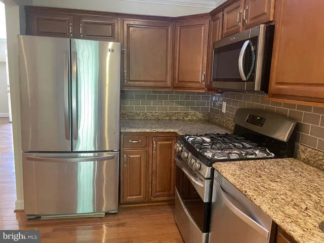 a kitchen with granite countertop a refrigerator stove and microwave