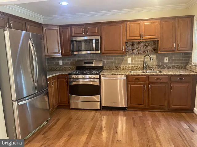 a kitchen with stainless steel appliances granite countertop a stove a sink dishwasher a refrigerator and a microwave