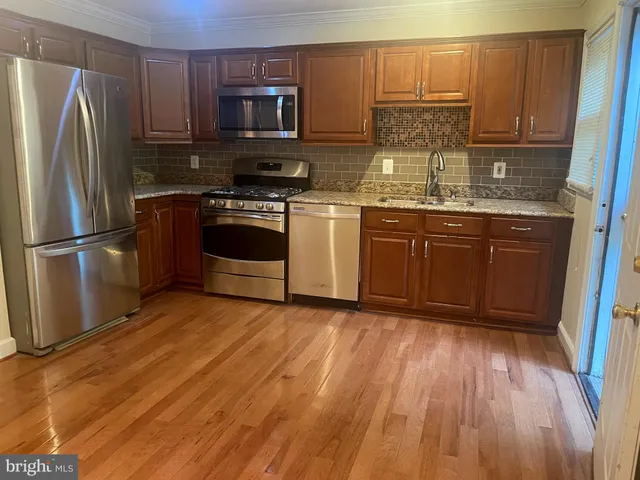 a kitchen with a sink wooden floor and stainless steel appliances