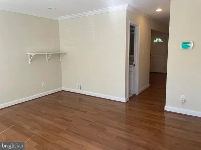 a view of an empty room with wooden floor and closet
