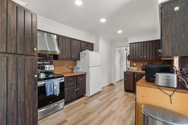 a kitchen with granite countertop wooden cabinets a stove a oven a refrigerator and a oven with wooden floor