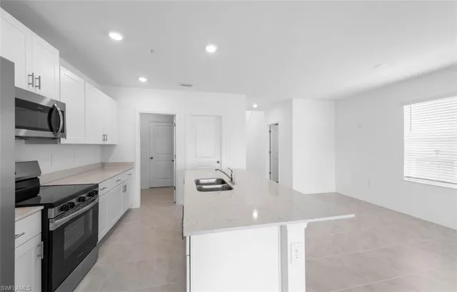 a large kitchen with stainless steel appliances kitchen island granite countertop a refrigerator a stove a sink and a microwave