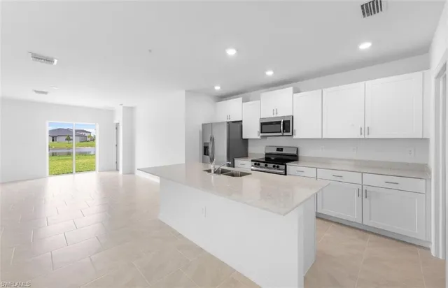a kitchen with granite countertop a sink a counter top space stainless steel appliances and cabinets