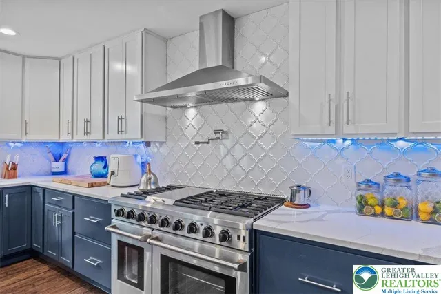 a kitchen with stainless steel appliances kitchen island granite countertop a refrigerator a stove and white cabinets with wooden floor