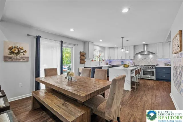 a living room with stainless steel appliances furniture wooden floor and a kitchen view