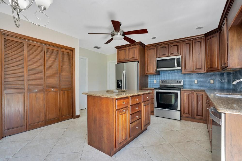 2088 Golden Arm Road Deltona, FL 32738 - Photo 14 of 51 a kitchen with stainless steel appliances granite countertop a stove top oven a sink dishwasher and a refrigerator with wooden cabinets