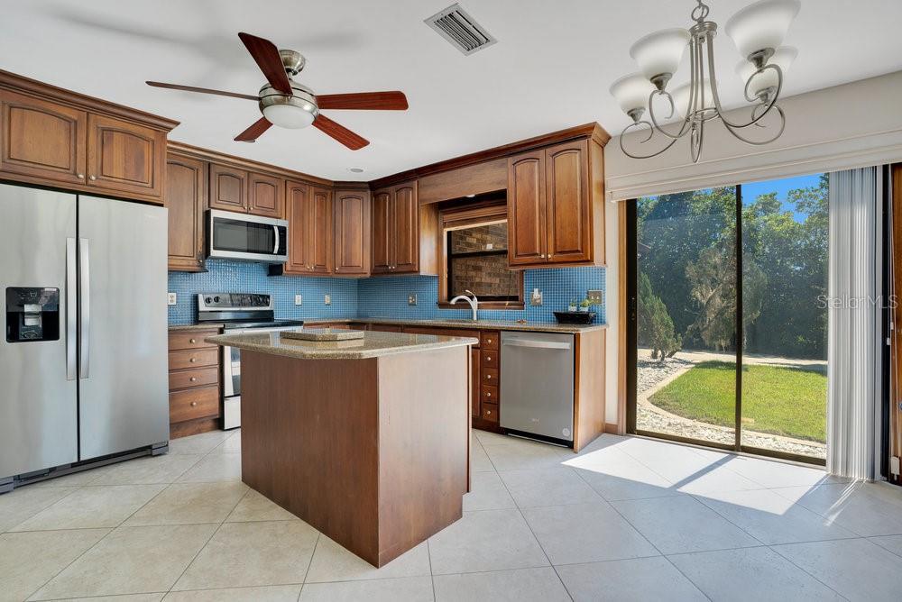 2088 Golden Arm Road Deltona, FL 32738 - Photo 16 of 51 a kitchen with granite countertop a refrigerator a sink a stove top oven a cabinetry and a chandelier