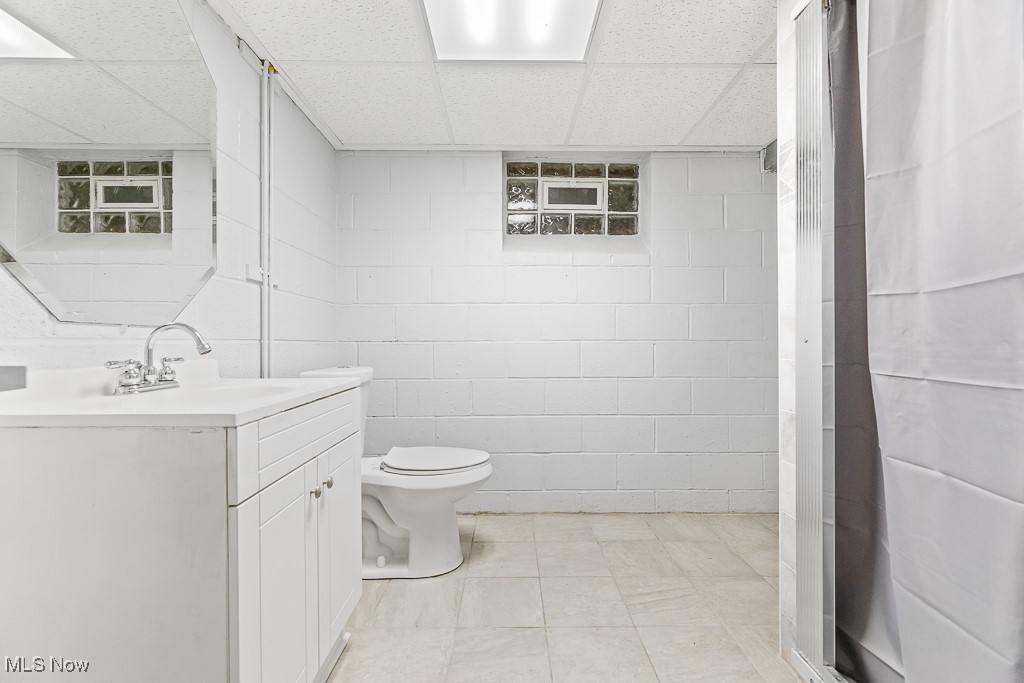 9049 Prospect Road Strongsville, OH 44149 - Photo 30 of 50 Bathroom with a paneled ceiling, tile patterned flooring, tile walls, toilet, and vanity