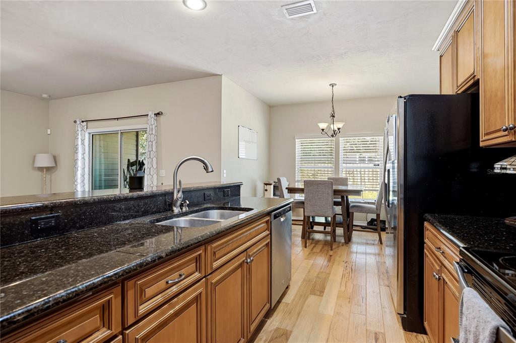 7550 Southwest 81st Way Gainesville, FL 32608 - Photo 13 of 31 a kitchen with granite countertop a stove a sink a dining table and chairs