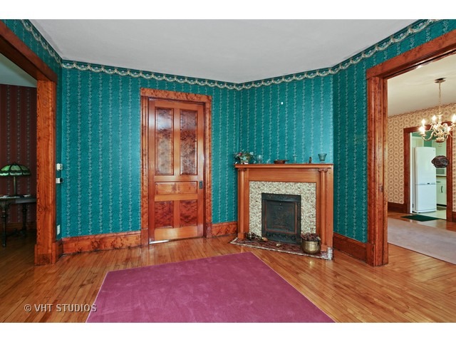 721 North Spring Street Elgin, IL 60120 - Photo 6 of 16 an empty room with wooden floor fireplace and windows