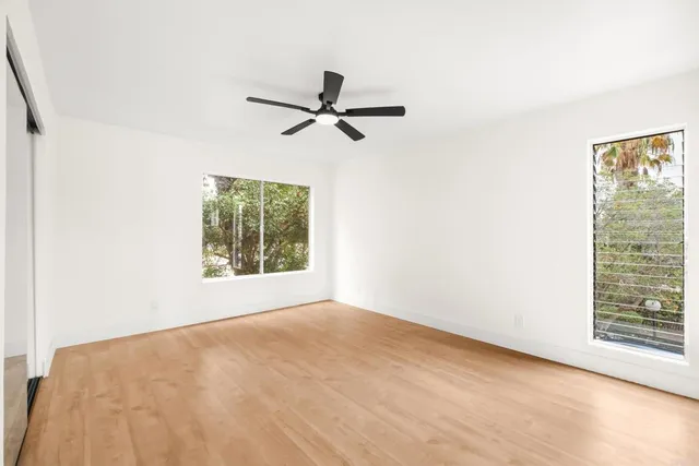 a view of empty room with wooden floor and ceiling fan