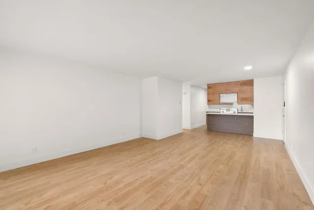 a large white kitchen with kitchen island a sink dishwasher a stove and a refrigerator with wooden floor