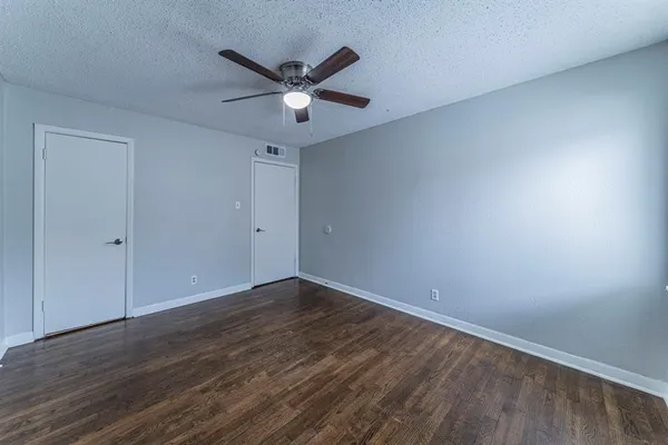 an empty room with wooden floor fan and windows