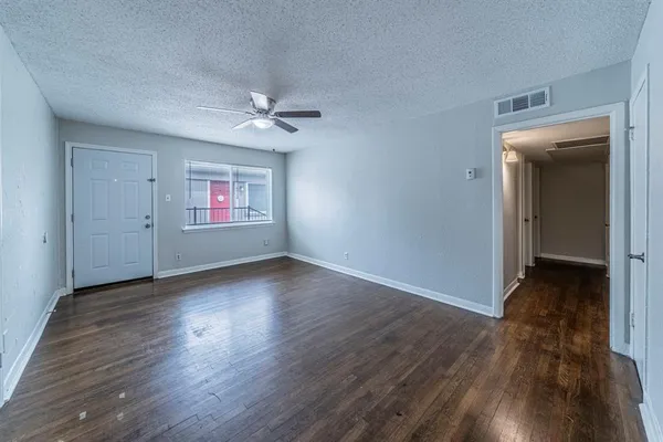an empty room with wooden floor chandelier fan and windows
