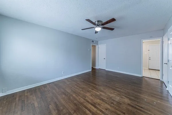 an empty room with wooden floor and a ceiling fan