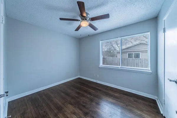 an empty room with wooden floor ceiling fan and windows