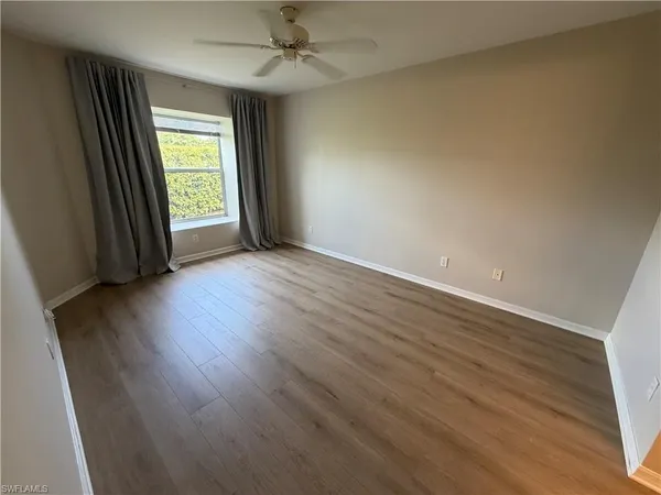 an empty room with wooden floor fan and windows