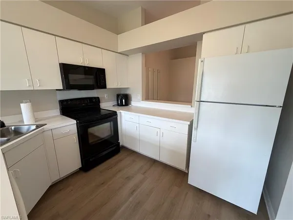 a kitchen with a refrigerator a stove top oven a sink and white cabinets