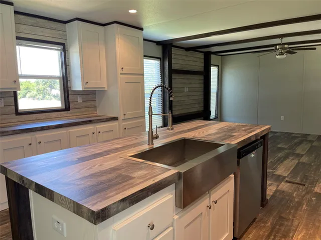 a view of kitchen island a sink wooden floor and a window