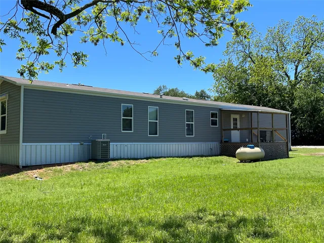 a front view of house with yard and tree in the background