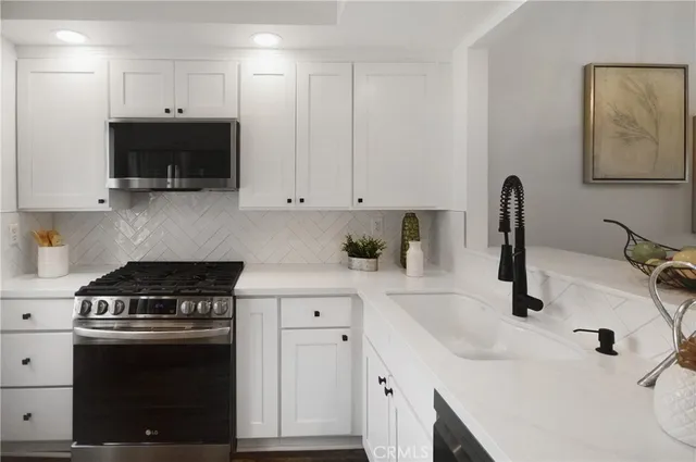 a kitchen with stainless steel appliances a sink a stove a microwave and cabinets