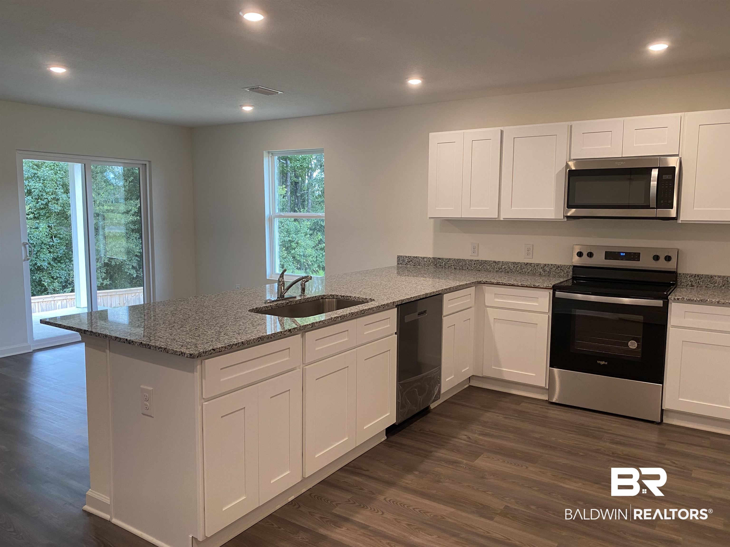 21676 Yosemite Boulevard Fairhope, AL 36532 - Photo 3 of 19 Kitchen featuring dark wood-type flooring, sink, white cabinets, kitchen peninsula, and stainless steel appliances