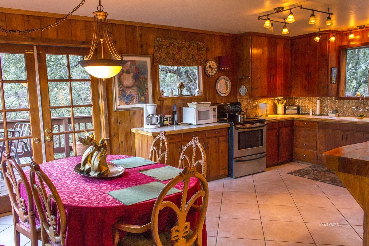 25120 Foster Lake Road Idyllwild, CA 92549 - Photo 13 of 31 a kitchen with stainless steel appliances granite countertop a sink a stove and a dining table with wooden cabinet