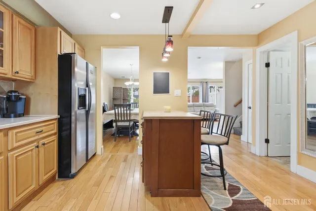 a kitchen with stainless steel appliances granite countertop a refrigerator a microwave oven a dining table and chairs with wooden floor