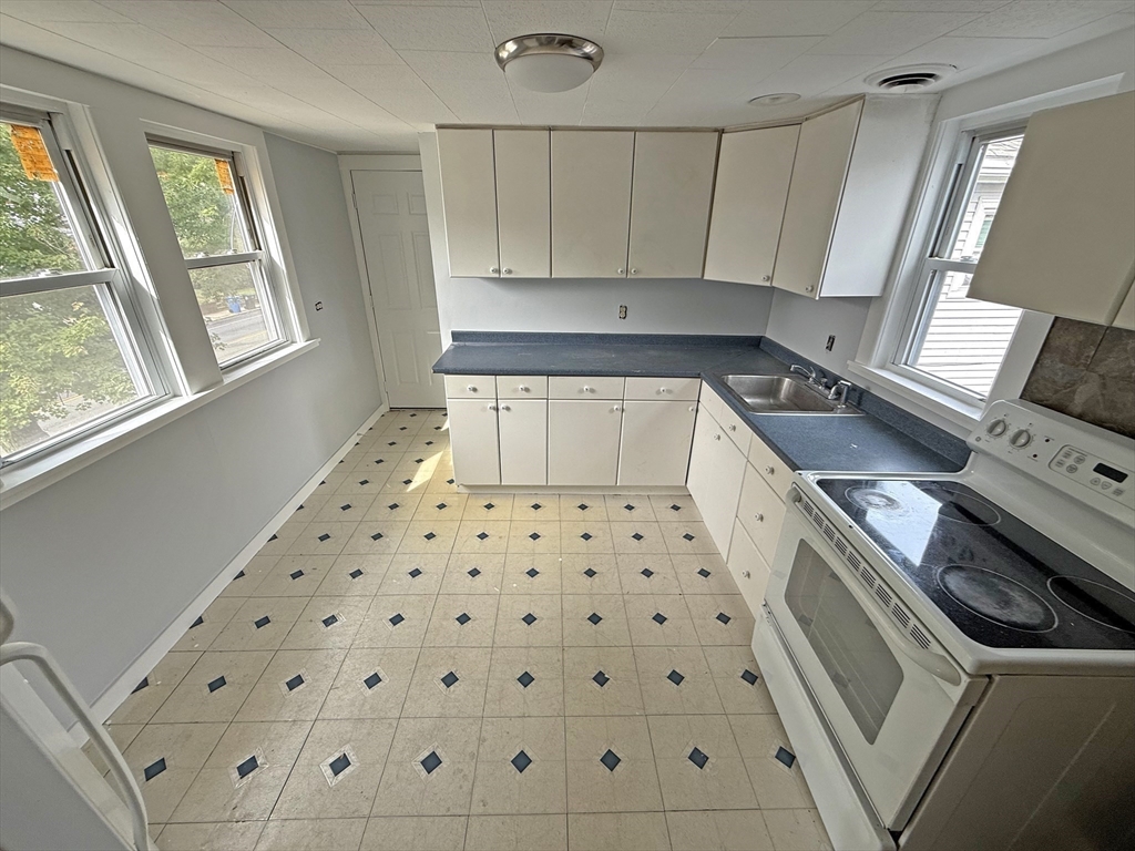 135-137 Temple Street Whitman, MA 02382 - Photo 12 of 15 a kitchen with granite countertop white cabinets and black appliances