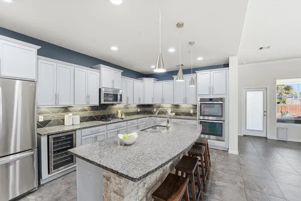 a kitchen with a stove a sink a refrigerator and chairs