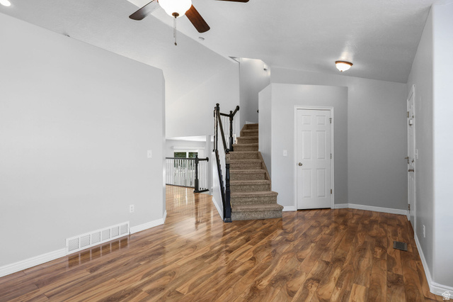 142 East 2675th Street South Clearfield, UT 84015 - Photo 6 of 49 Open-concept interior featuring wood-finish flooring, a carpeted staircase with dark railings, and a white paneled door