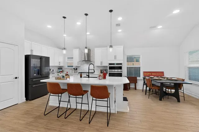 a kitchen with stainless steel appliances kitchen island granite countertop a table chairs and a refrigerator