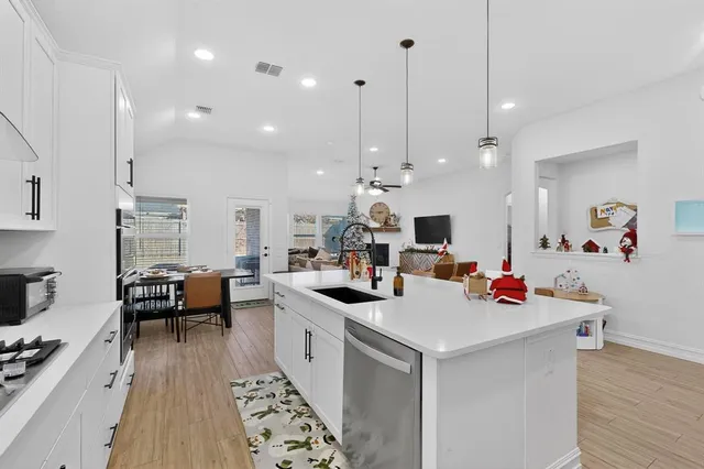 a view of a kitchen with kitchen island stainless steel appliances a stove a sink a center island and living room view