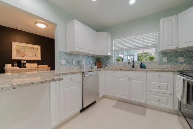 a kitchen with granite countertop white cabinets white stainless steel appliances with a sink and dishwasher