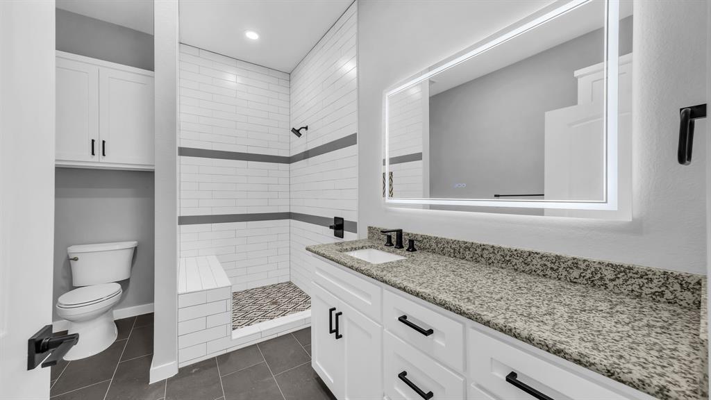 3 Quarter Loop Poolville, TX 76487 - Photo 28 of 40 a bathroom with a granite countertop sink a toilet and a mirror