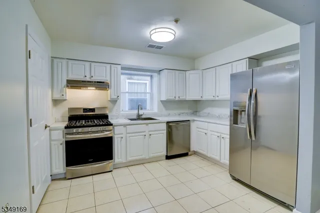 a kitchen with stainless steel appliances granite countertop a stove a refrigerator and a sink