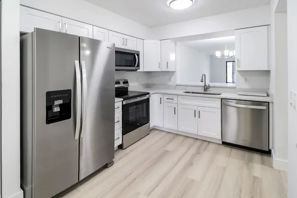 a kitchen with stainless steel appliances granite countertop a refrigerator a stove top oven a sink and dishwasher