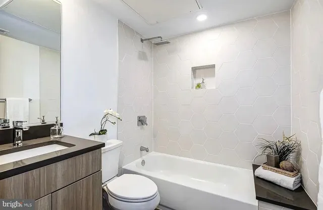 a bathroom with a bathtub shower sink mirror vanity and toilet