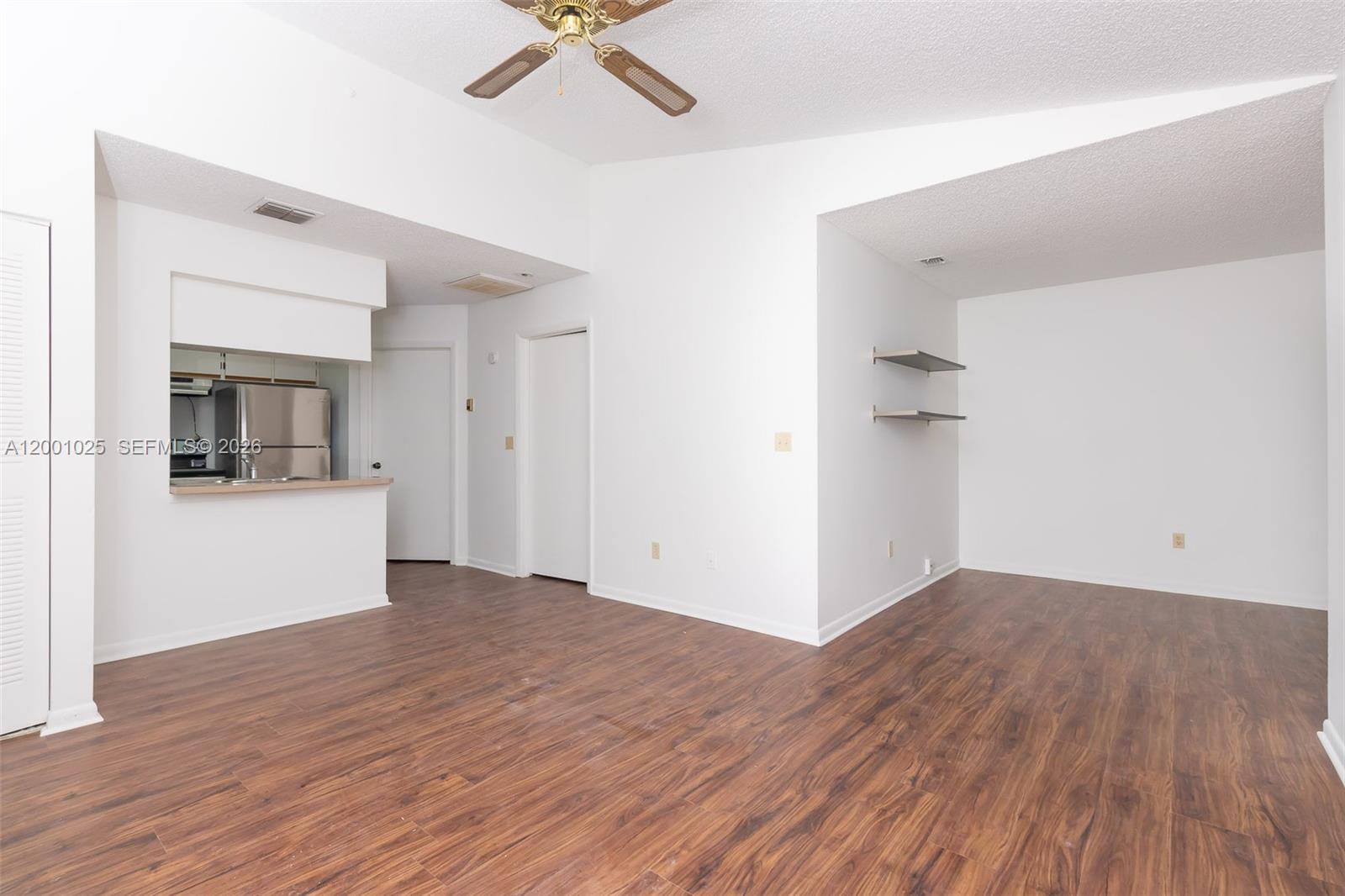18310 Northwest 68th Avenue, Unit L Hialeah, FL 33015 - Photo 4 of 21 a view of empty room with wooden floor and kitchen view