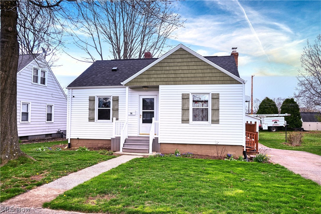 View of front of house with a chimney, a front lawn, and roof with shingles