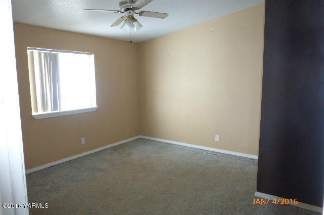 201 Mini Pines Road Yakima, WA 98903 - Photo 11 of 11 an empty room with a chandelier fan and windows