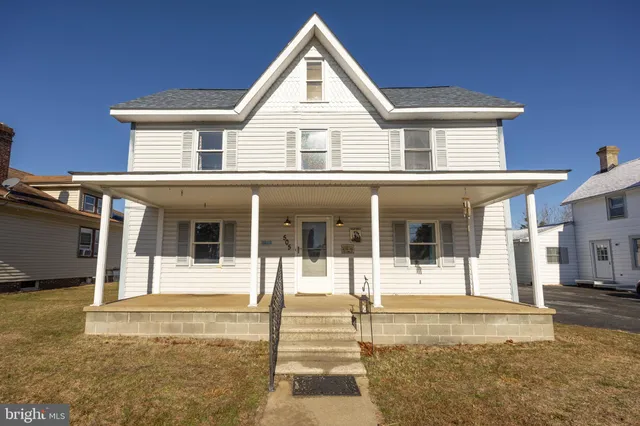 a view of a white house with large windows next to a road