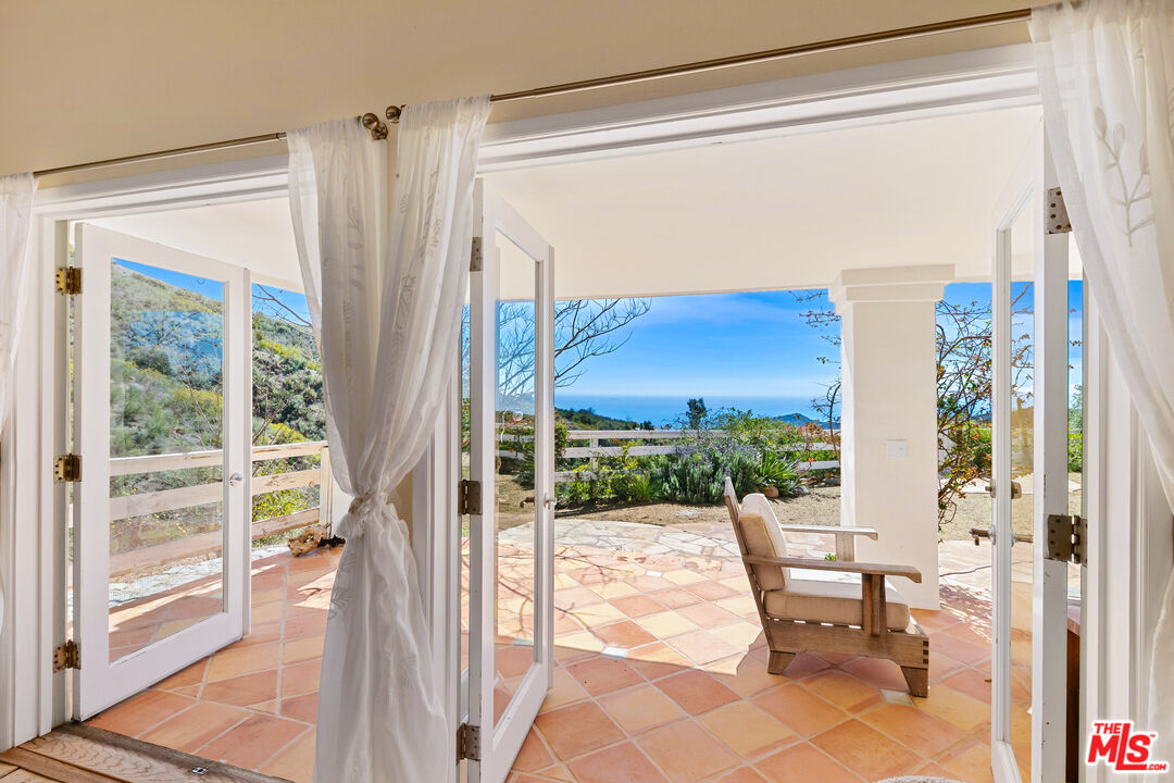 2302 Latigo Canyon Road Malibu, CA 90265 - Photo 1 of 30 a view of a balcony with chairs and floor to ceiling window with wooden floor