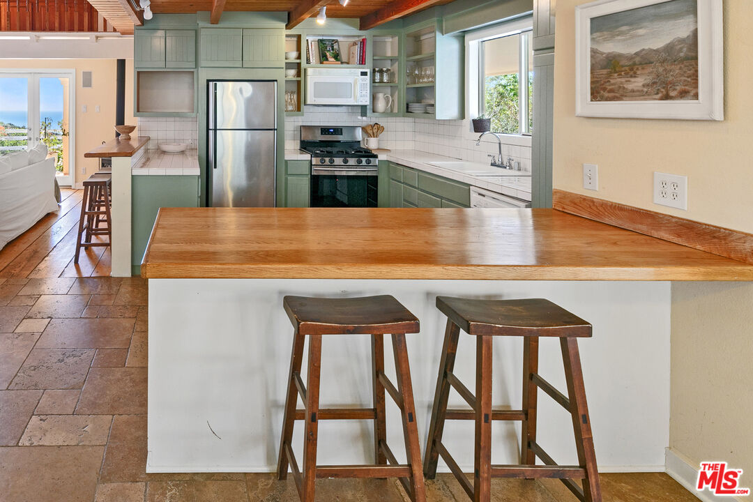 2302 Latigo Canyon Road Malibu, CA 90265 - Photo 14 of 30 a kitchen with stainless steel appliances granite countertop a stove a refrigerator a dining table and chairs with wooden floor