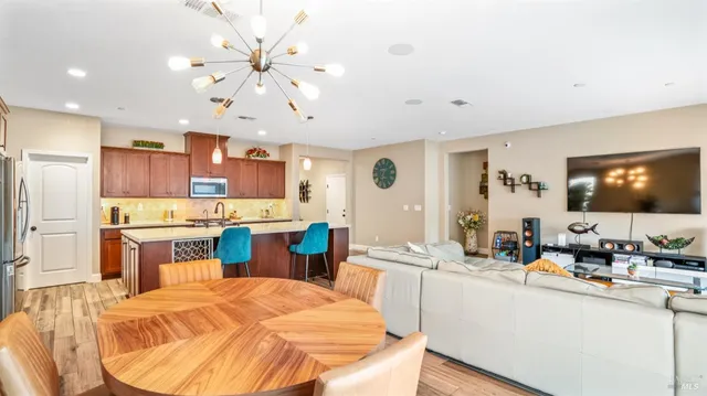 a kitchen with stainless steel appliances kitchen island granite countertop a sink dishwasher and white cabinets with wooden floor