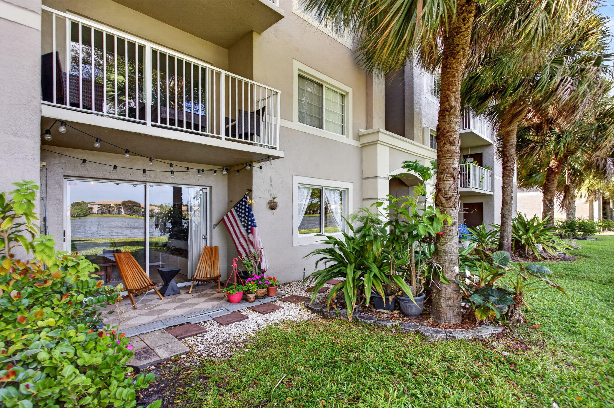 5011 Wiles Road, Unit 104 Coconut Creek, FL 33073 - Photo 2 of 43 a view of a house with a small yard and palm trees