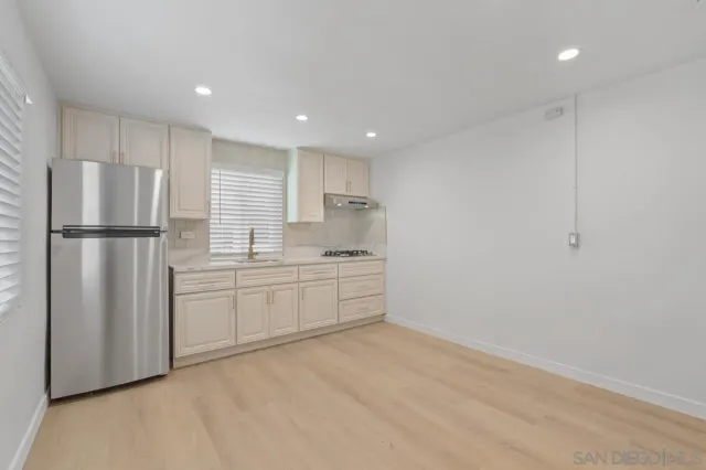 a kitchen with a refrigerator and white cabinets