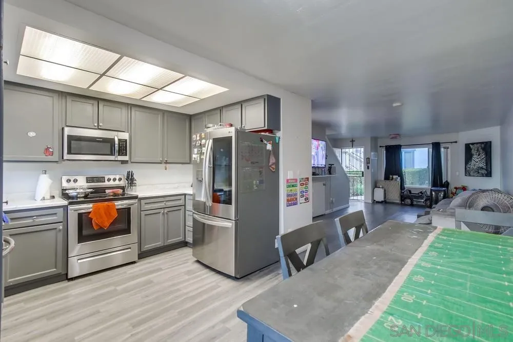 3433 Los Mochis Way Oceanside, CA 92056 - Photo 17 of 45 a kitchen with stainless steel appliances granite countertop a refrigerator a stove top oven a sink dishwasher a dining table and chairs with wooden floor