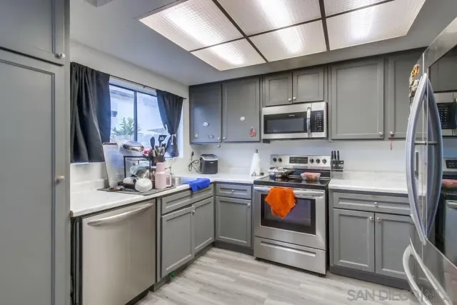 a kitchen with stainless steel appliances granite countertop a sink a stove top oven a refrigerator and dishwasher